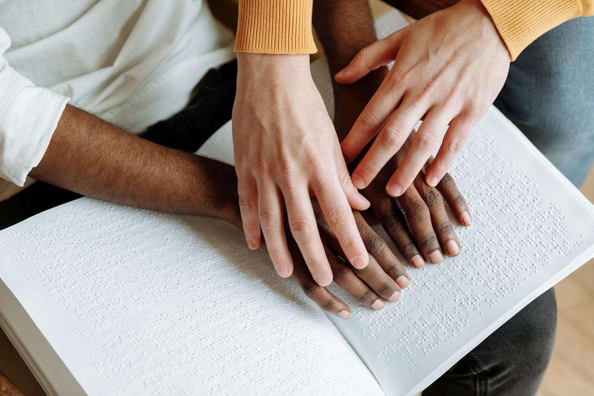 Hands resting together on an open braille book